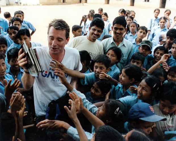 John Wood, cercado por criancinhas nepalesas sedentass de livros