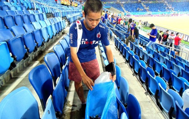 Torcedor japonês recolhendo lixo após o jogo contra a Grécia